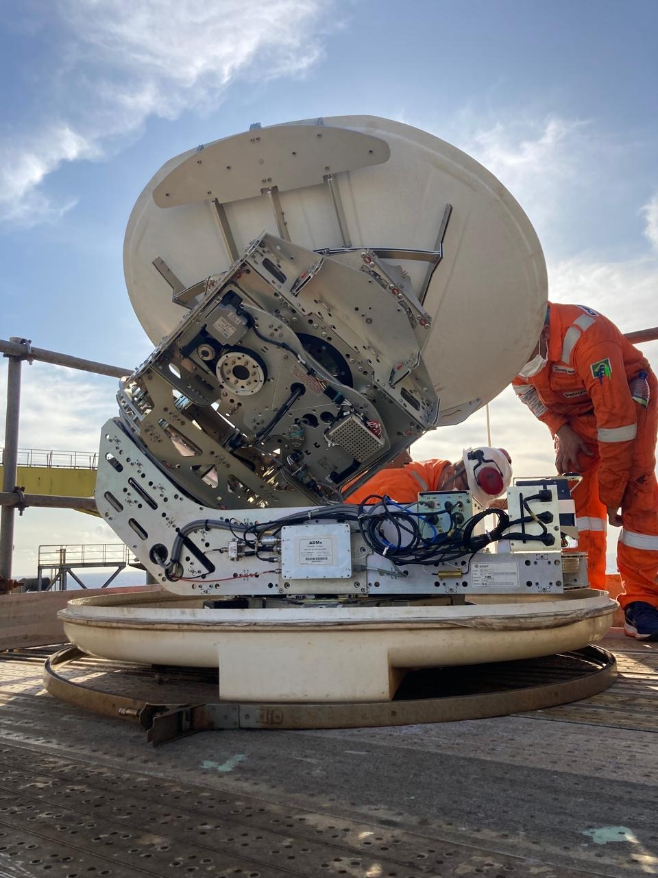 Equipe em trabalho de instalação de antena VSAT marítima em unidade offshore